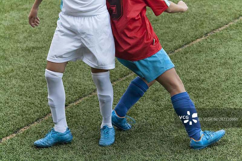 两名男孩踢足球时的腿部镜头图片素材