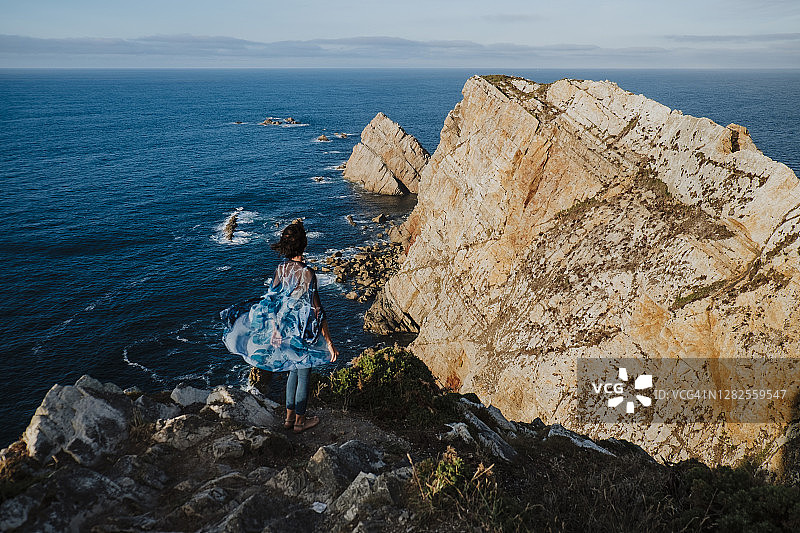 中年妇女站在岩石上看海在假期图片素材