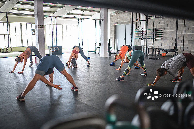 男女运动员在健身房做热身伸展运动图片素材