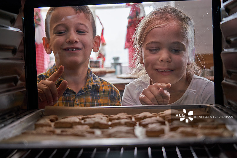 小孩子在烤箱里烤姜饼图片素材