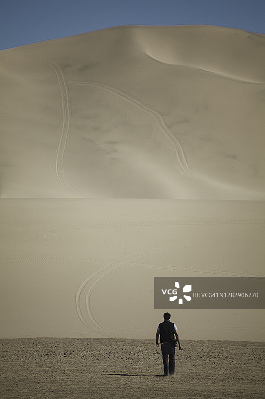 一个人走向沙漠中非常高的沙丘图片素材