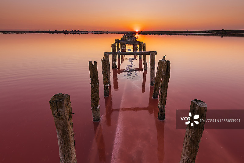 日落时的粉色盐湖。用于盐提取的木结构图片素材