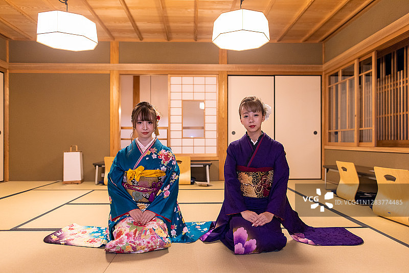 在日本Ryokan酒店的榻榻米房间里，穿着Furisode和服的年轻女性们坐在高跟鞋上图片素材