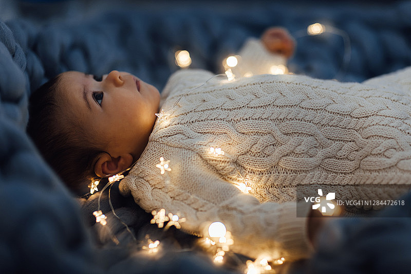 新生儿穿着针织的身体躺在羊毛的美利奴毛毯和花环。图片素材