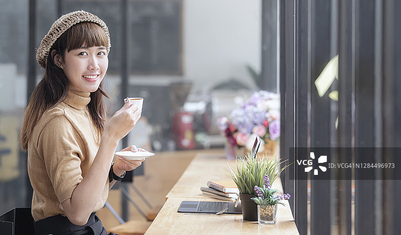 年轻迷人的女人放松喝热咖啡在咖啡店。图片素材