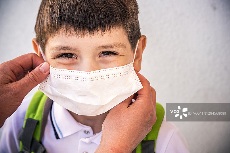 孩子戴着防护口罩防止污染或病毒的特写镜头，学童戴着防护口罩防止pm2.5空气污染的特写镜头。图片素材