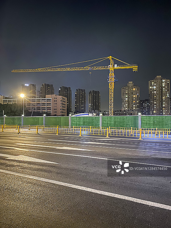 中国杭州的夜晚，空荡荡的街道和路边的起重机图片素材