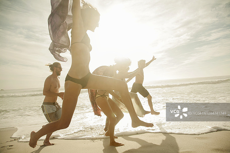 阳光灿烂的日子，快乐的朋友们在海滩上跳来跳去图片素材