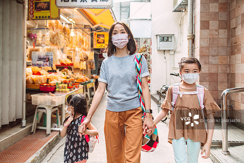 妈妈和女儿们戴着防护口罩在香港传统的街市上漫步图片素材