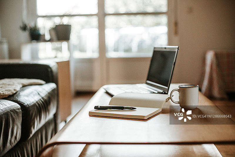 咖啡，笔记本电脑和一个带笔的白色笔记本可以在家里工作图片素材