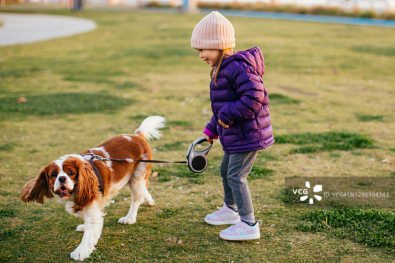 可爱的女孩和一只漂亮的狗在户外公园散步图片素材