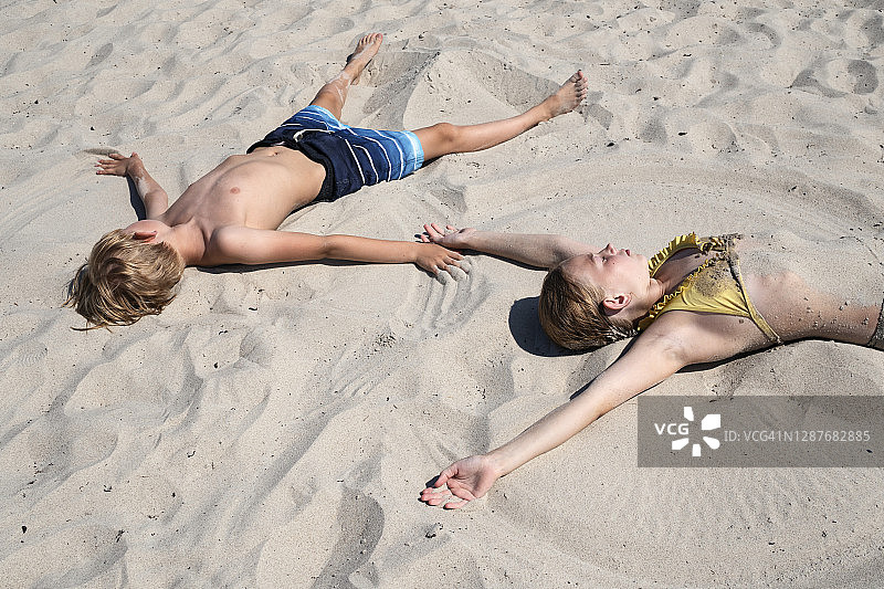 男孩和女孩躺在沙滩上图片素材