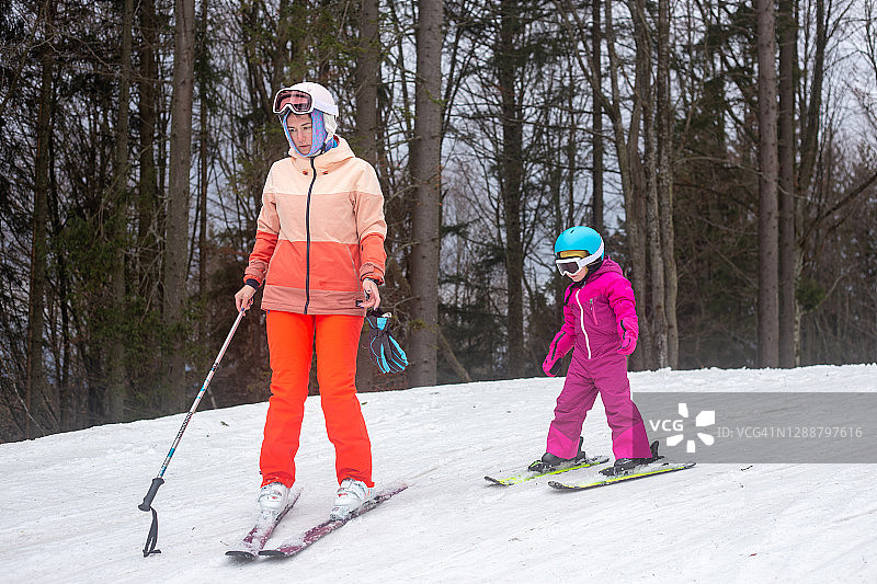 那孩子正和他母亲一起滑雪。图片素材