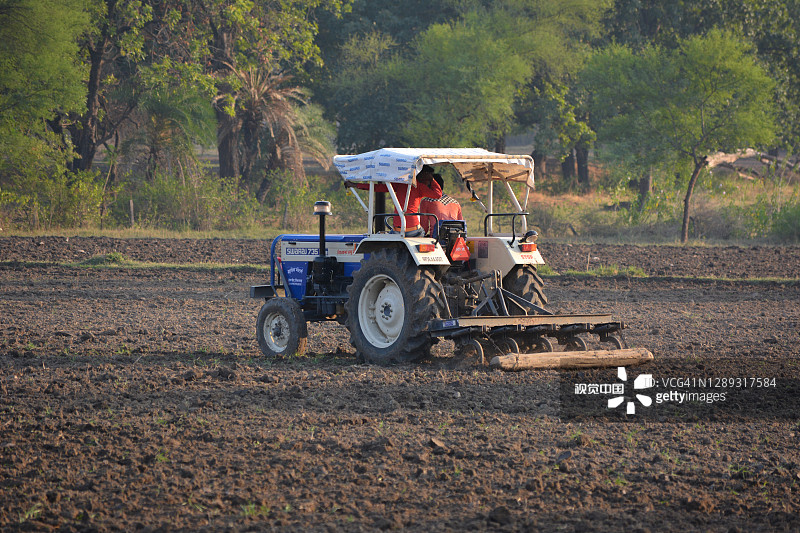 印度农民用拖拉机准备用耙播种。图片素材
