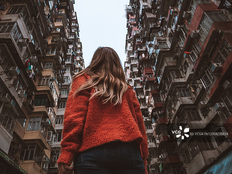 香港，一名女子抬头看着拥挤的公寓图片素材