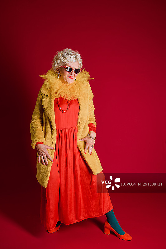 一位金发的老妇人穿着红色的长裙，穿着黄色的毛皮大衣图片素材