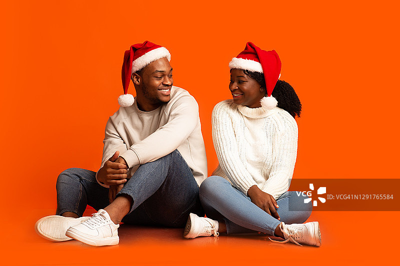 正面的黑人男女戴着圣诞老人帽互相微笑图片素材