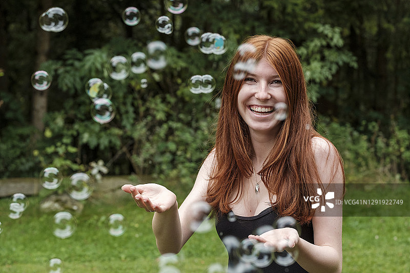 快乐的女人在后院玩肥皂泡图片素材