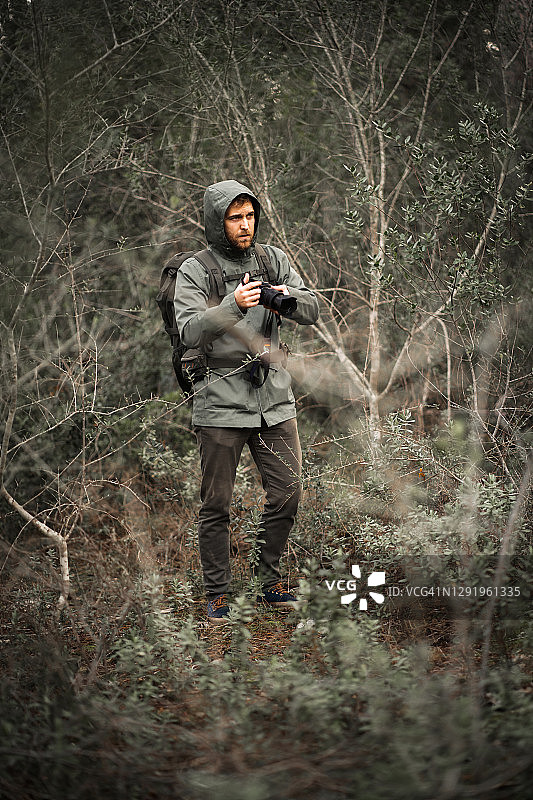 摄影师在灌木丛中举起相机伪装着大自然图片素材