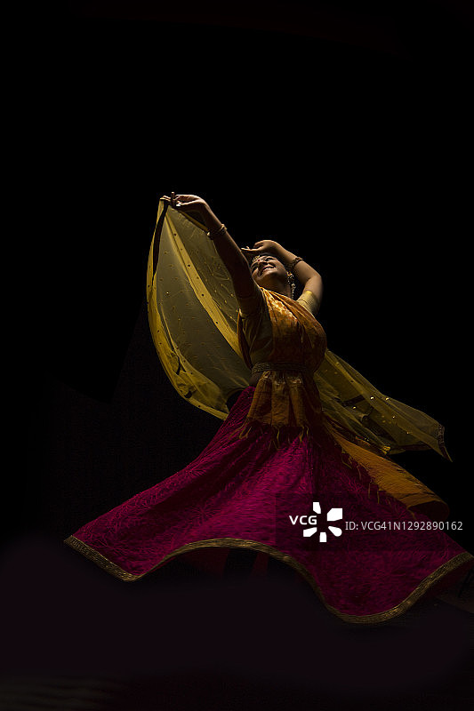 卡塔克舞者在黑暗背景前的表演中优雅地旋转。图片素材