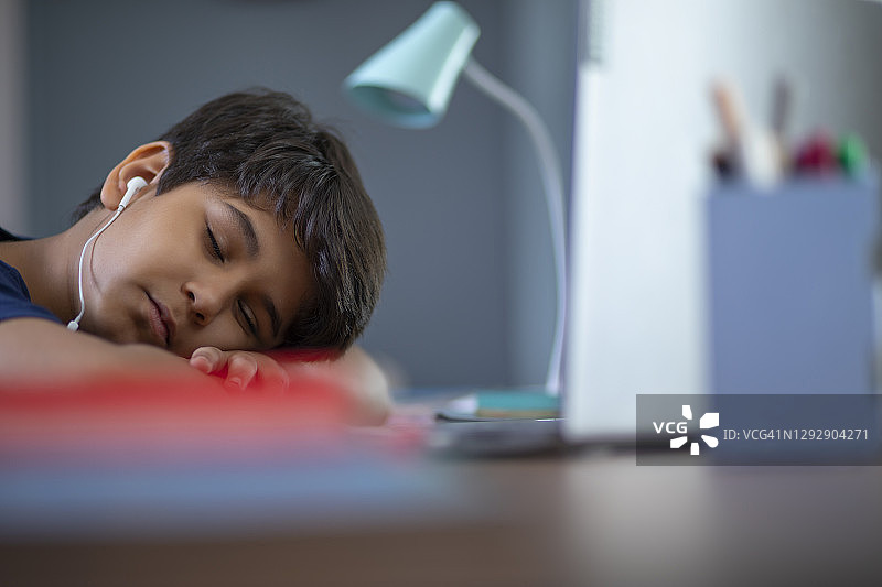 一个小男孩在上网络课的时候睡在笔记本电脑前图片素材
