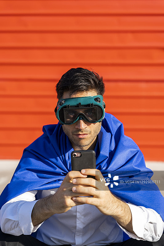 商人戴着智能手机，穿着超级英雄斗篷和VR眼镜图片素材