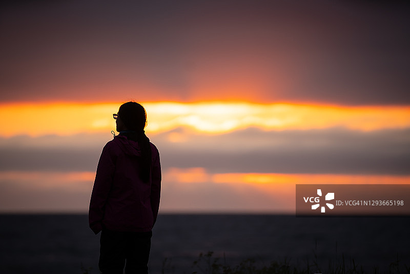 挪威吉姆斯øy，一名年轻女子在观看令人惊叹的日落图片素材