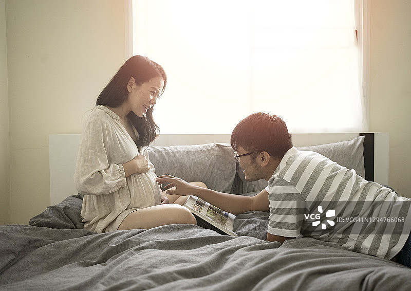 美丽的亚洲孕妇和她的丈夫感觉享受和愉快的谈话彼此在舒适的卧室图片素材