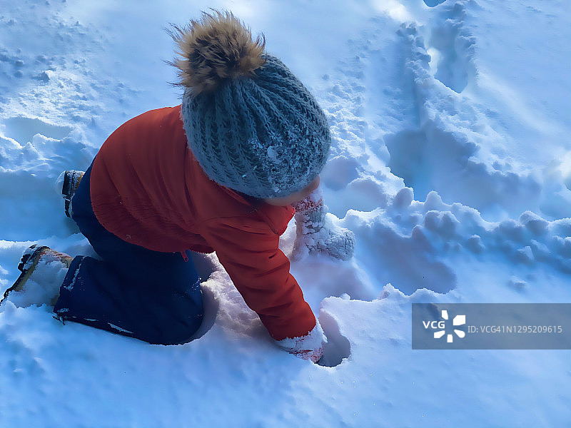 好玩的混血幼童喜欢在冬季暴风雪后的新鲜雪中玩耍图片素材