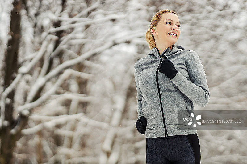 雪天里，女运动员在树林里跑步。冬天健身，健康生活，自然图片素材