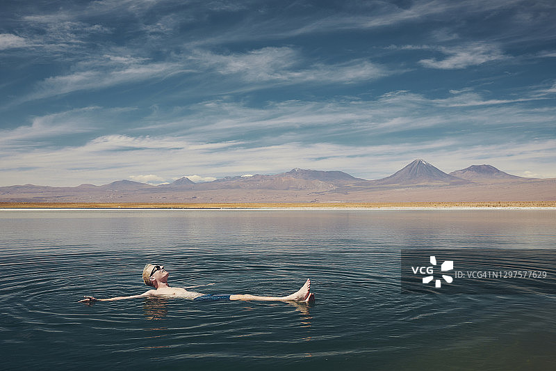 微笑着，快乐的人，放松地漂浮在阿塔卡马沙漠的盐湖上图片素材