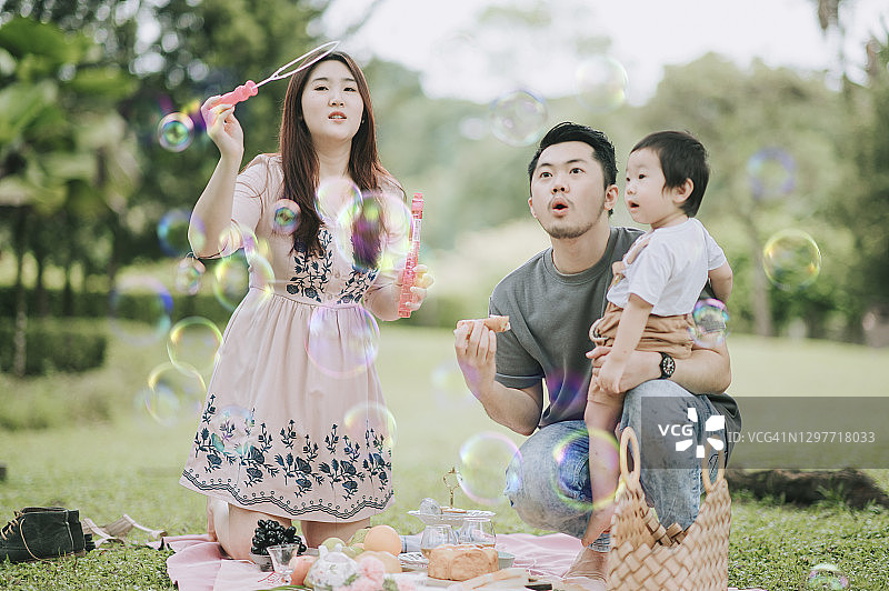 亚洲华人青年家庭玩泡泡享受户外野餐时间在周末图片素材