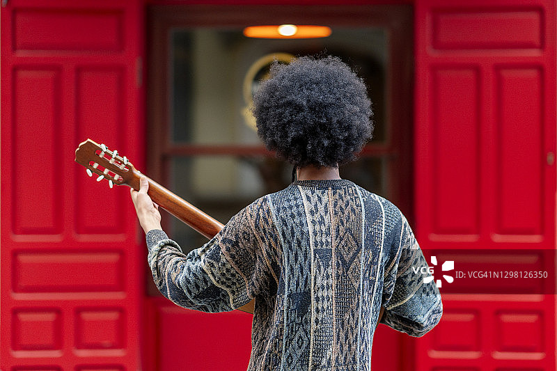一个年轻人站在大楼前弹吉他图片素材