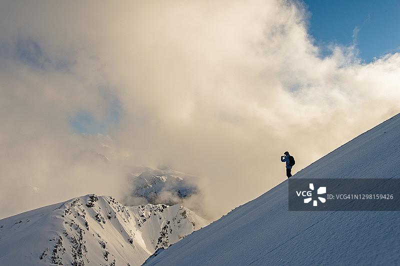 野外滑雪者停在陡峭的粉坡上，向外看图片素材