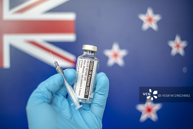 以新西兰国旗为背景的注射器新冠疫苗，冠状病毒SARS-CoV-2，疫苗接种图片素材