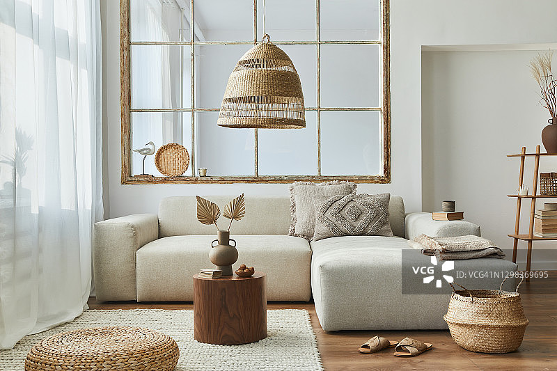 时尚的客厅内部设计模块化沙发，家具，木制茶几，藤装饰，吊灯，枕头，干花和优雅的配件在现代家居装饰。图片素材