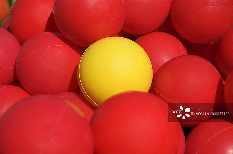 黄色的塑料球，周围是红色的球图片素材