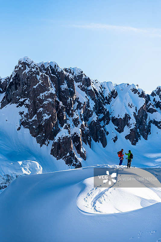 滑雪登山运动员攀登高耸的山脉下面的山脊线图片素材