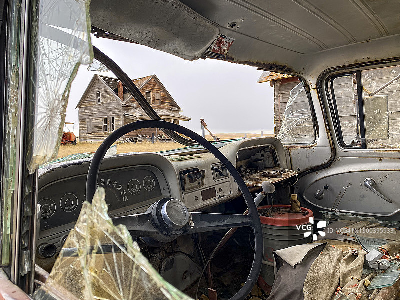 透过废弃农舍里一辆旧卡车的破挡风玻璃图片素材