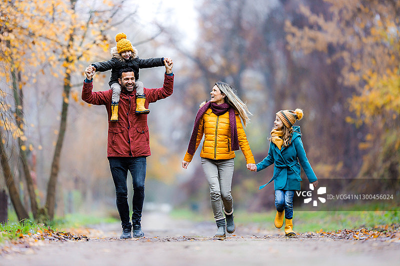幸福的家庭在秋天的一天在公园玩。图片素材