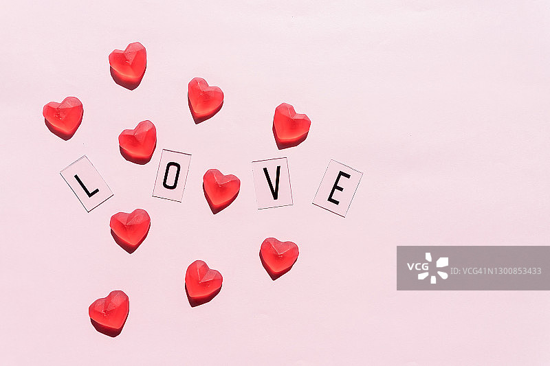 横幅。“爱”这个词。黑字用红心爱。粉红色的背景。情人节。爱,积极的情感。情绪背景。独家的关系。图片素材
