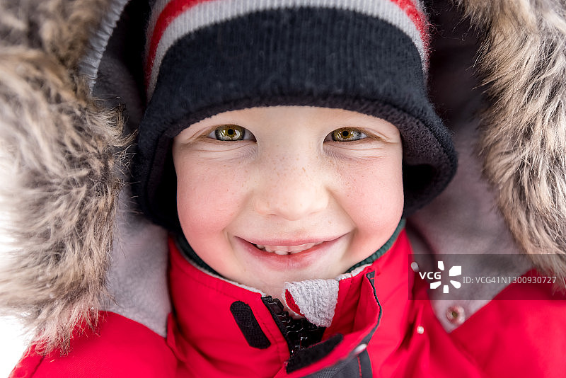 小男孩肖像在户外玩在冬天暴风雪和看相机图片素材