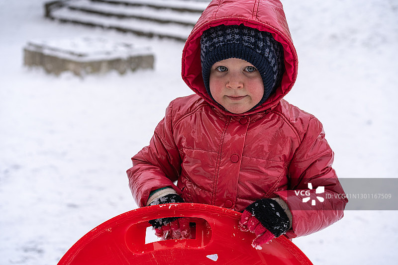 一个小女孩从冬天的滑梯上骑着雪橇图片素材