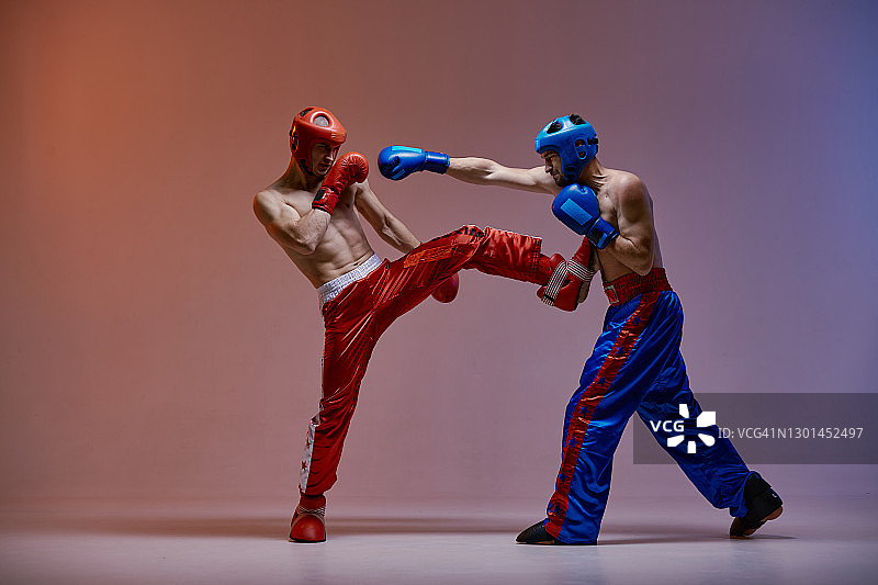 对打的两个战斗的家伙在拳击手套在战斗中在红蓝色的光，武术，混合战斗的概念图片素材
