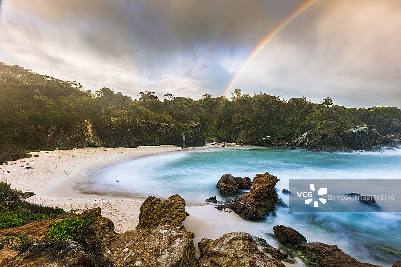 海滩海湾与戏剧性的云形成彩虹在蓝绿色的海洋图片素材