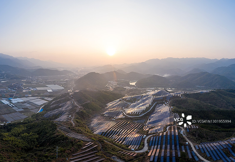 日落时分山上的太阳能发电厂鸟瞰图图片素材