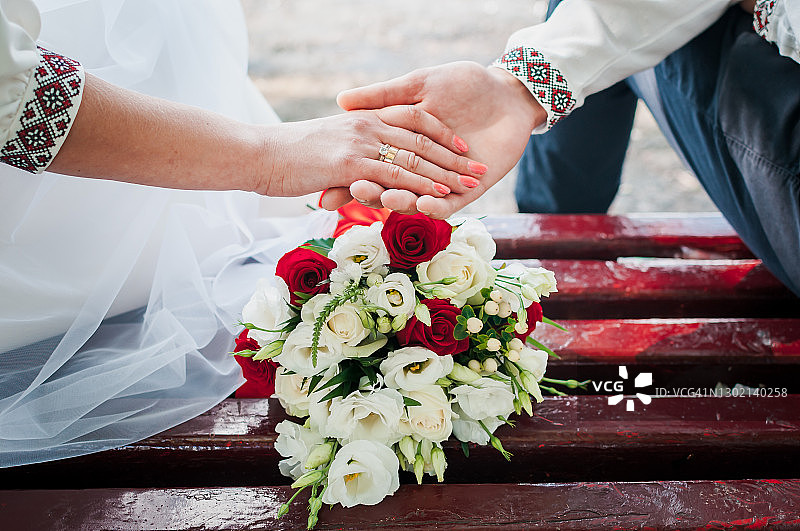 在婚礼花束的背景下，新婚夫妇手牵着手图片素材