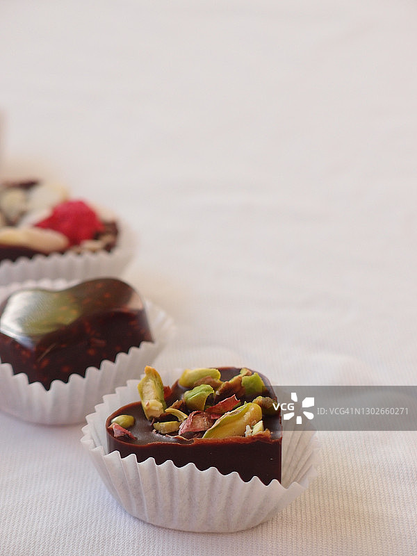 白色桌布上放着美味的自制巧克力、坚果和浆果。巧克力糖果合上图片素材