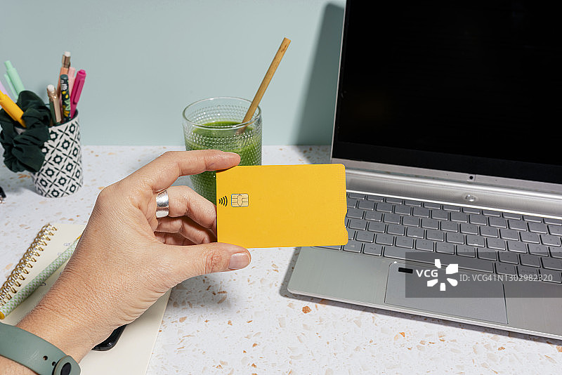 一名女子用信用卡通过笔记本电脑和健康的绿色果汁进行网上购物图片素材
