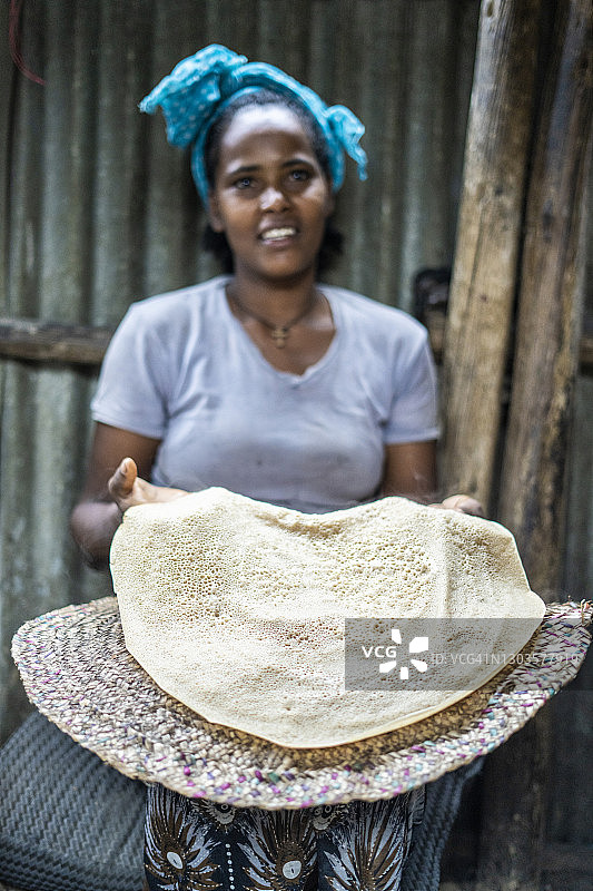 在非洲埃塞俄比亚阿法尔地区的贝黑尔，一名妇女正在展示传统的英杰拉面饼图片素材